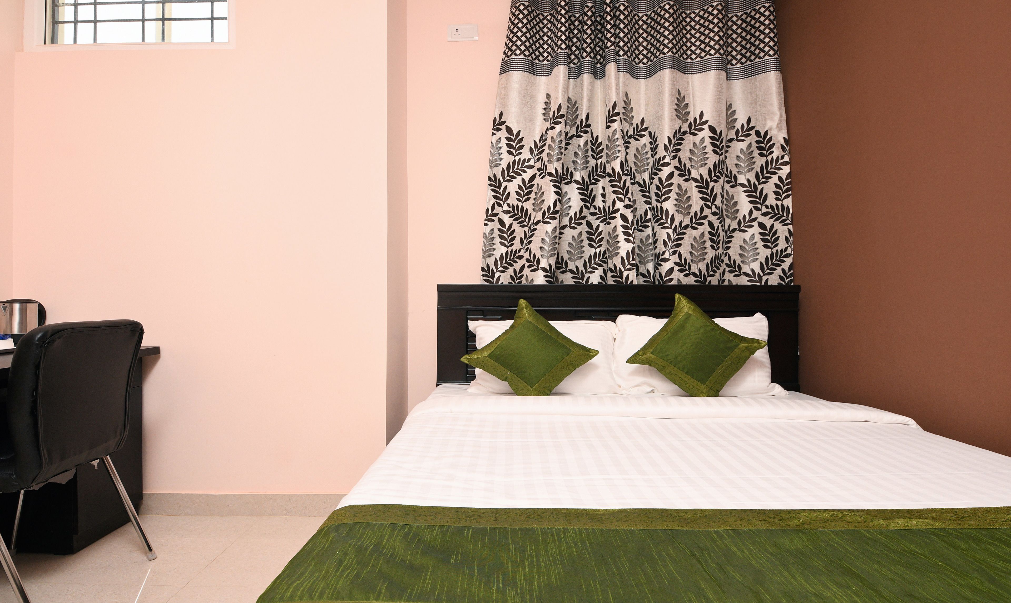 A bedroom with a bed, two pillows, a desk, and a chair.