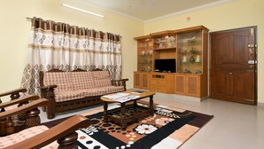 A living room with a sofa, coffee table, and a cabinet with glass doors. - Itsy Hotels Shivas Kuteera (Bengaluru)