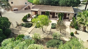 Una villa con patio, muros de piedra y tejado de tejas.