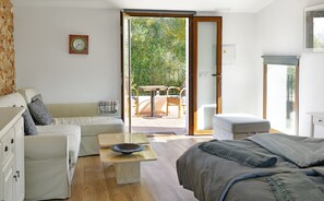 A modern bedroom with a bed, a sofa, a small table, and a view of an outdoor patio with a table and chairs. - Agroturismo Fincahotel Son Pou AG/322 (Felanitx)