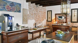 Una cocina con cafetera, una mesa de comedor con una botella de vino y un candelabro.