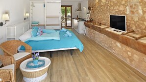 Un dormitorio con una cama grande, televisión, pared de piedra y encimera de madera.