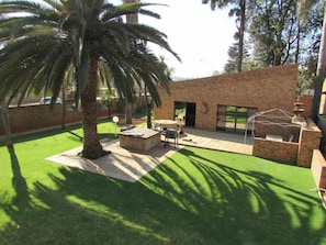 Un patio con pared de ladrillo, mobiliario exterior y una palmera.