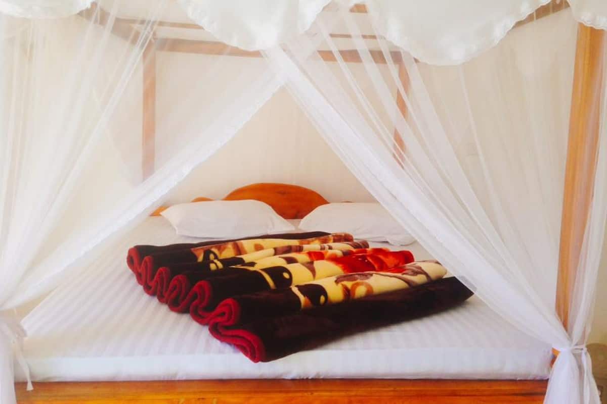 A bed with a canopy, pillows, and a blanket.