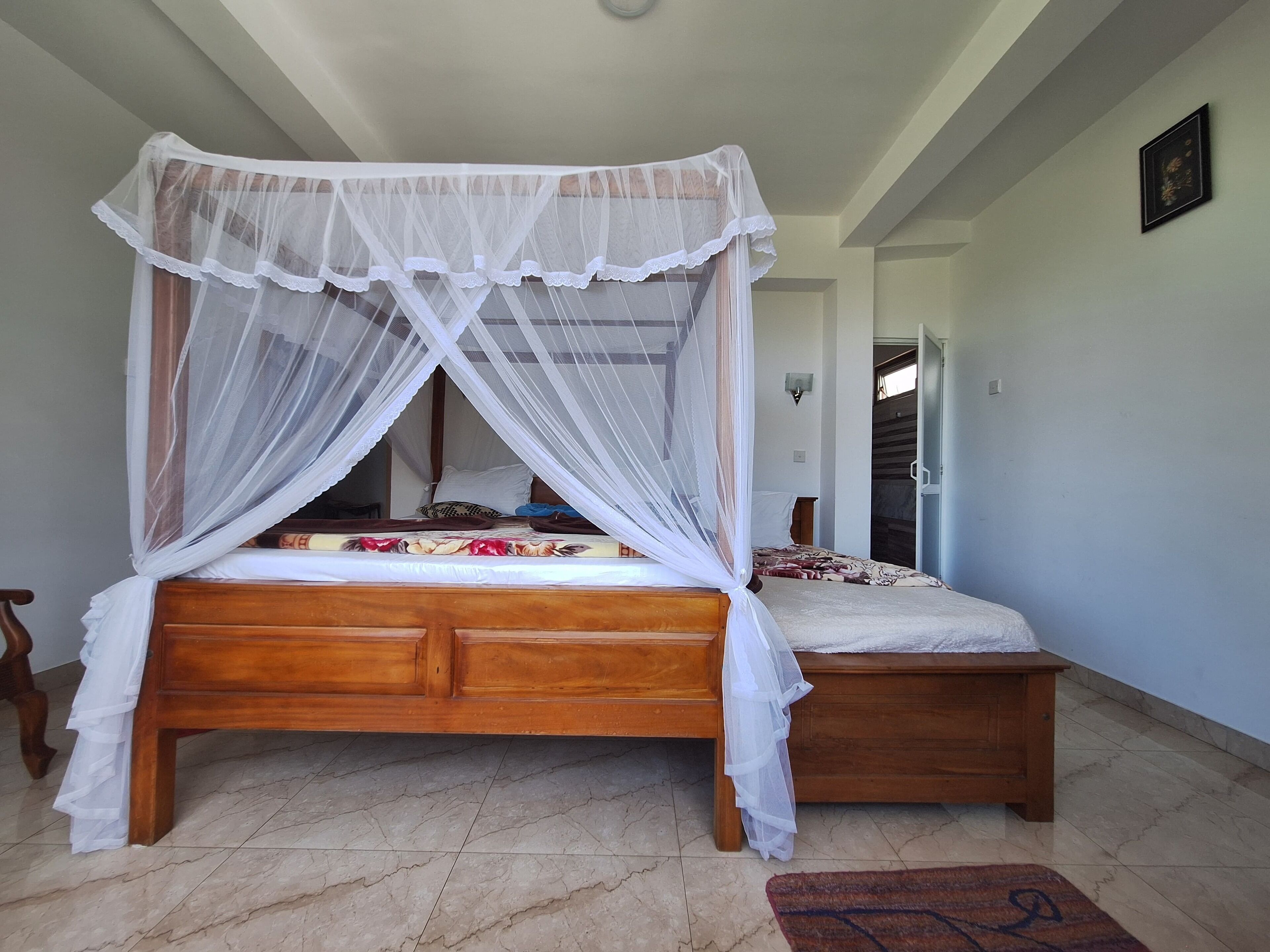 A bedroom with a wooden bed, white canopy, and a small bedside table.