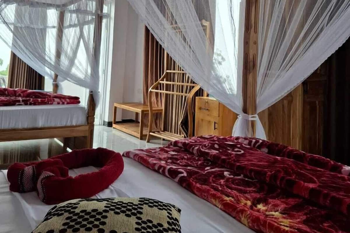 A room with a bed, a chair, and a canopy bed with a red and black patterned blanket.