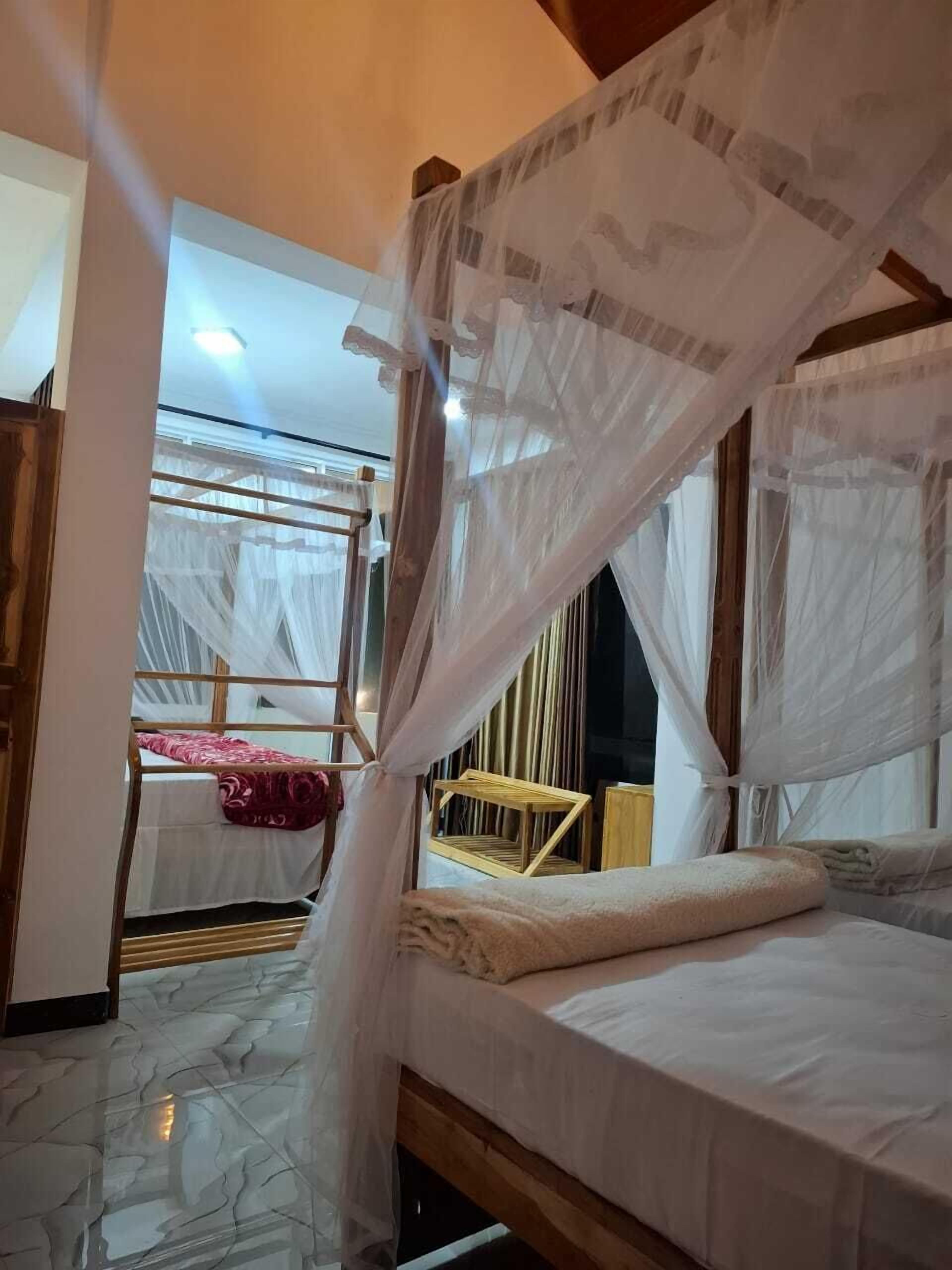 A room with a wooden bed and a canopy bed with mosquito netting.