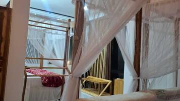 A room with a wooden bed and a canopy bed with mosquito netting.