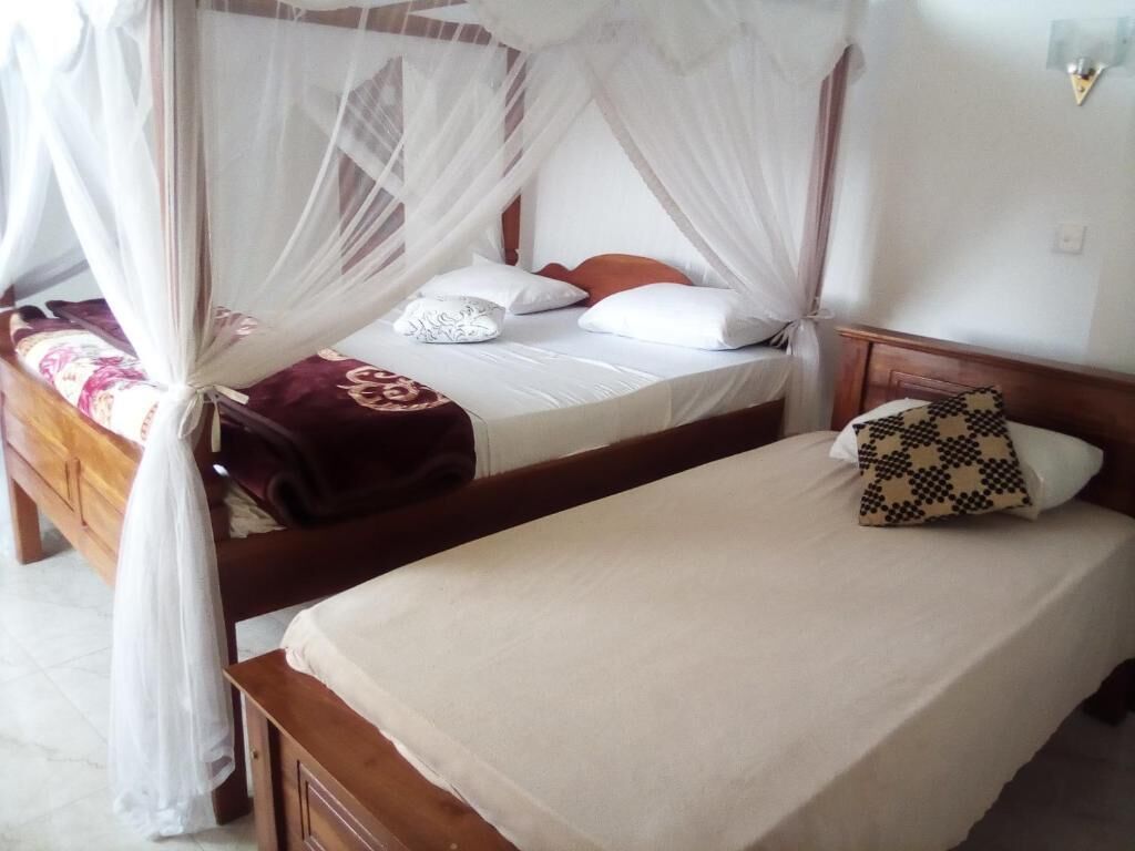 A bedroom with a bed under a canopy, a bedside table, and a nightstand.