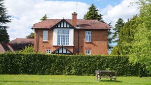 A two-story brick house with a gabled roof, a central window, and a chimney. - Catherines Court (Solihull)