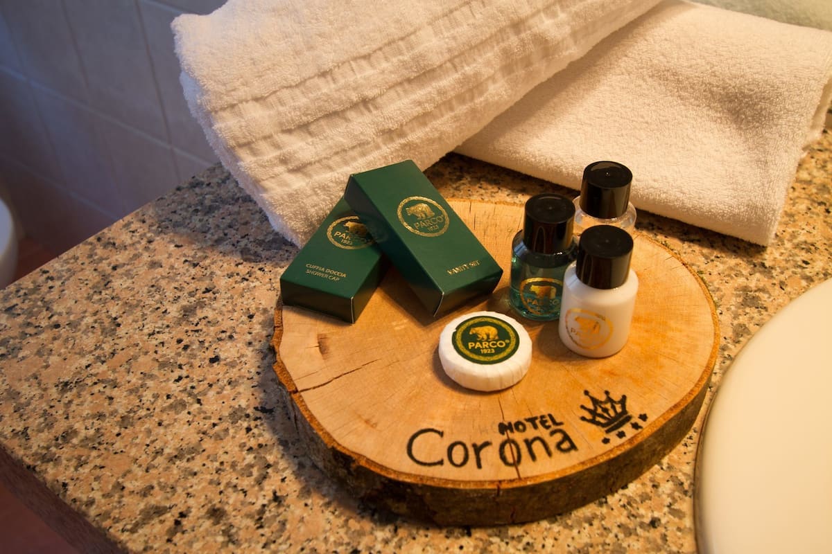 Una bandeja de madera con el nombre del hotel, un gorro de ducha y artículos de aseo sobre una encimera de baño.