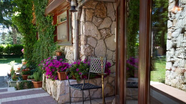 A stone building with a metal chair and potted plants outside. - Hotel Corona (Pescasseroli)