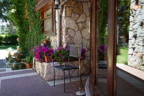A stone building with a metal chair and potted plants outside. - Hotel Corona (Pescasseroli)
