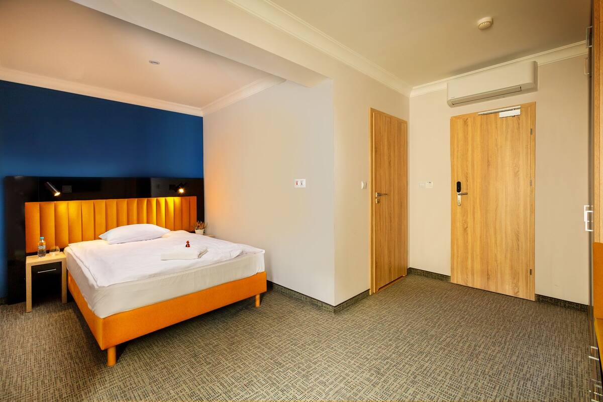 Una habitación de hotel con cama, mesita de noche y puerta de madera.