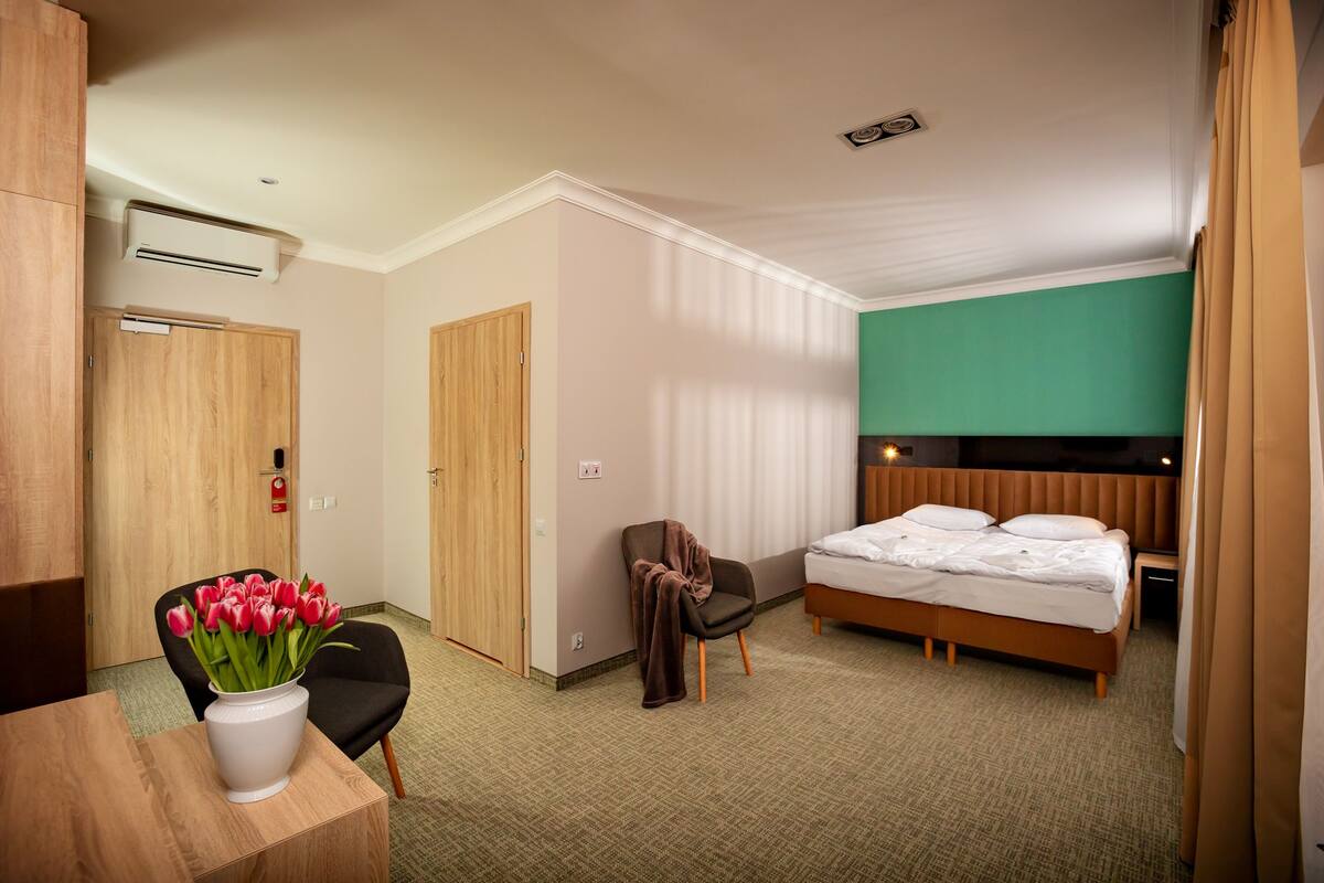 Una habitación de hotel con cama, una silla, un escritorio y un florero.
