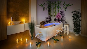 A spa room with a bathtub, candles, and decorative plants. - Akacja Medical Resort (Ciechocinek)
