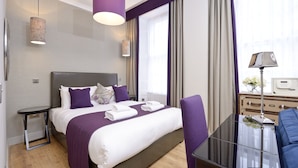 A modern hotel room with a large bed, a glass table, and a view of the city. - Destiny Scotland Charlotte SQ Apartments (Edinburgh)