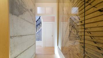 A narrow hallway with wooden flooring and a glass partition on one side.