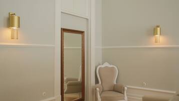 A room with a large mirror, a white chair, and two wall-mounted lights.