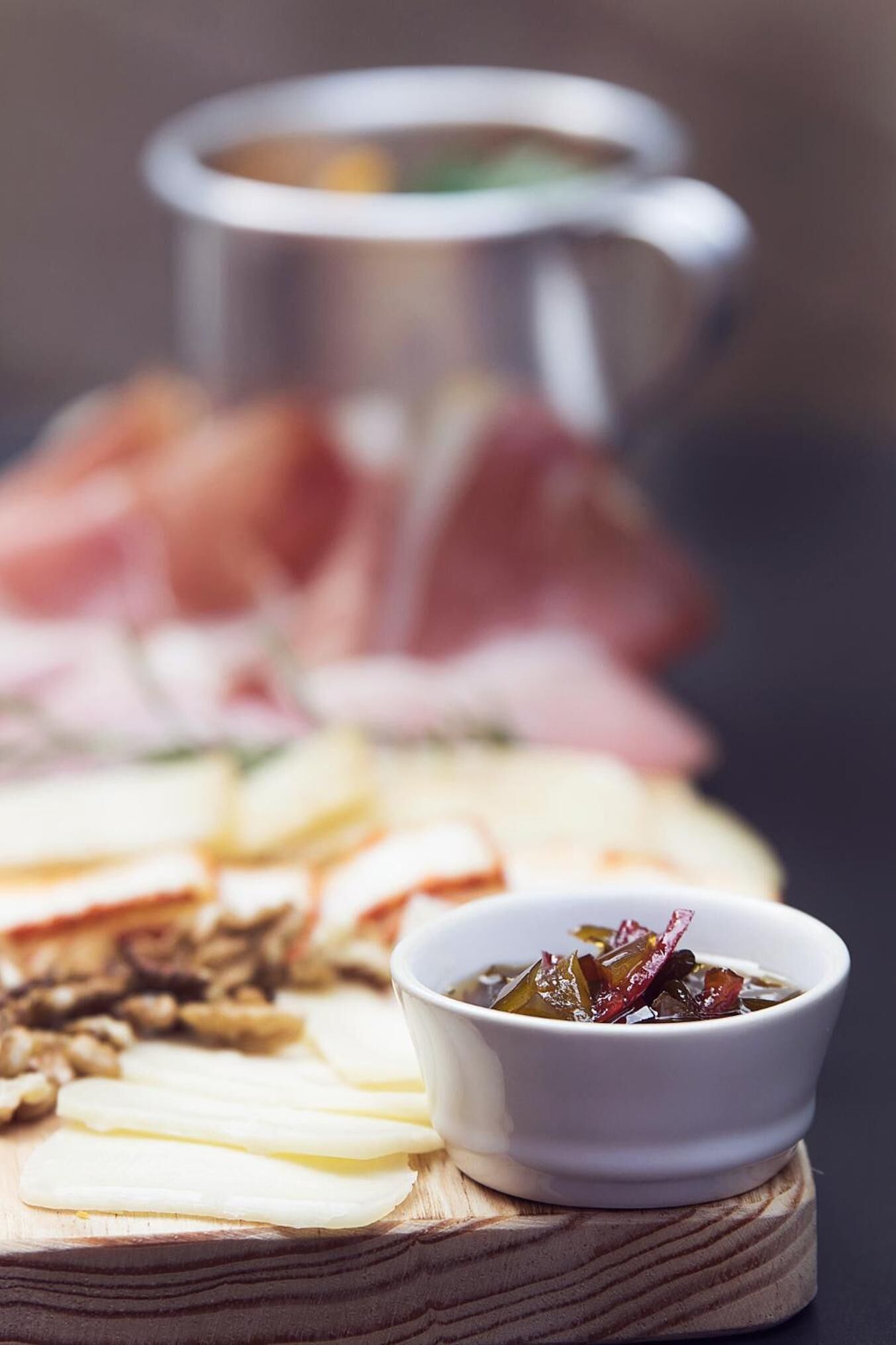 Una tabla de embutidos con diferentes carnes, quesos y encurtidos.