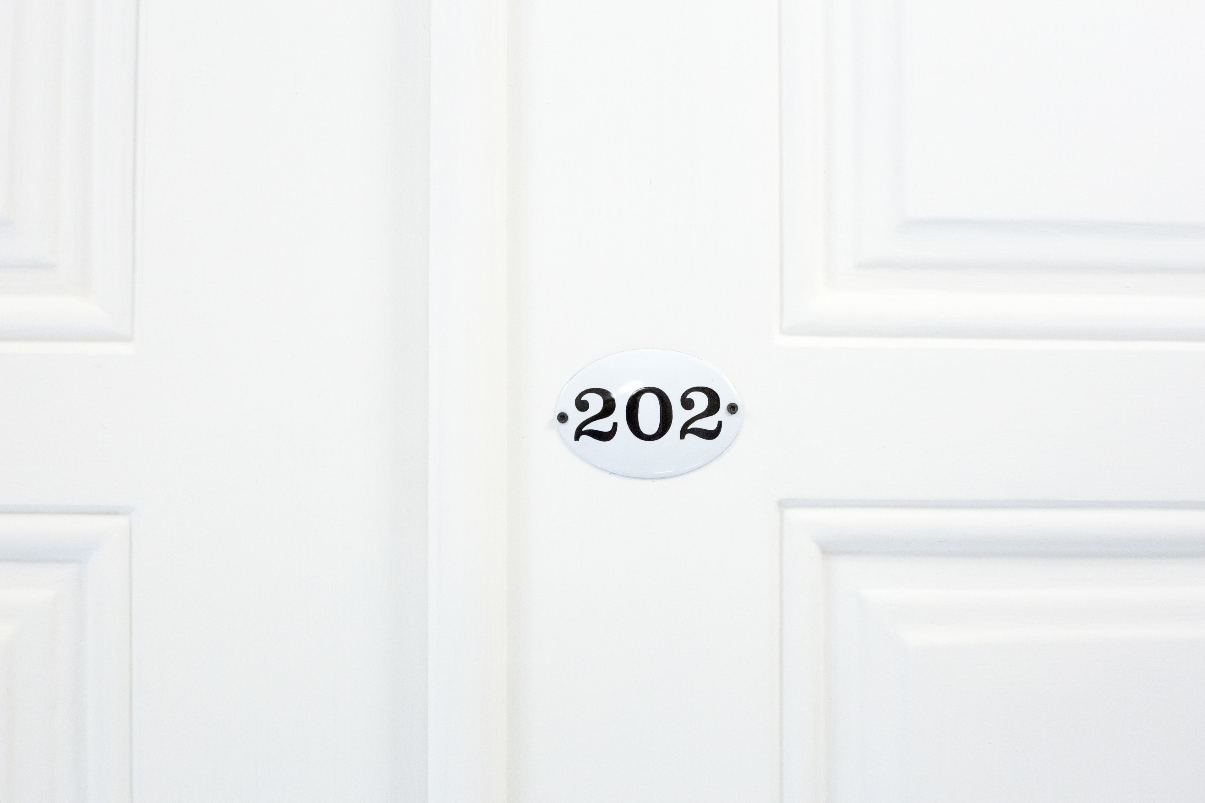 A white door with a number plate indicating room number 202.