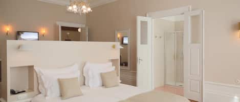 A spacious bedroom with a large bed, a chandelier, and a walk-in closet.