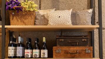 A shelf with wine bottles and a wicker basket with flowers.