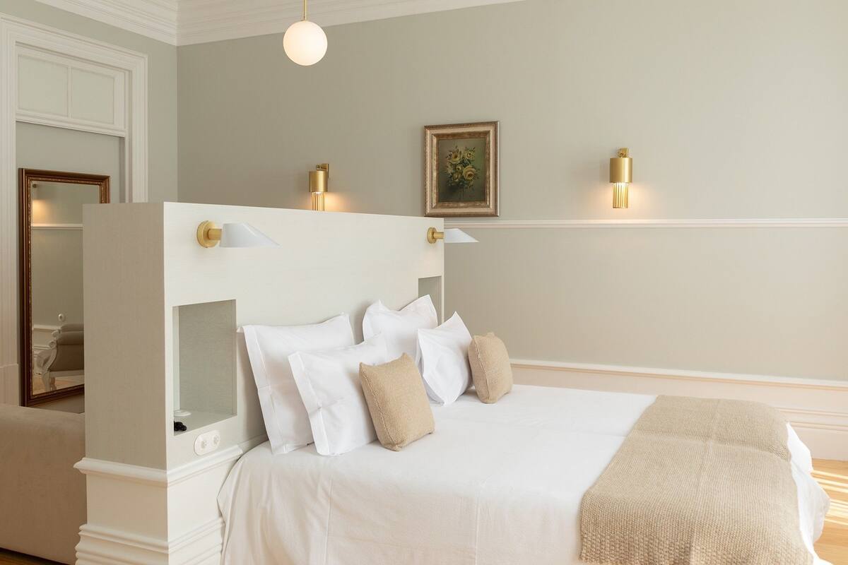 A neatly arranged bedroom with a large bed, bedside lamps, and a framed picture on the wall.