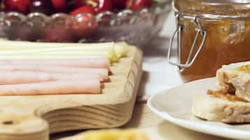 A table with food items including sliced ham, cherries, and a jar of honey.