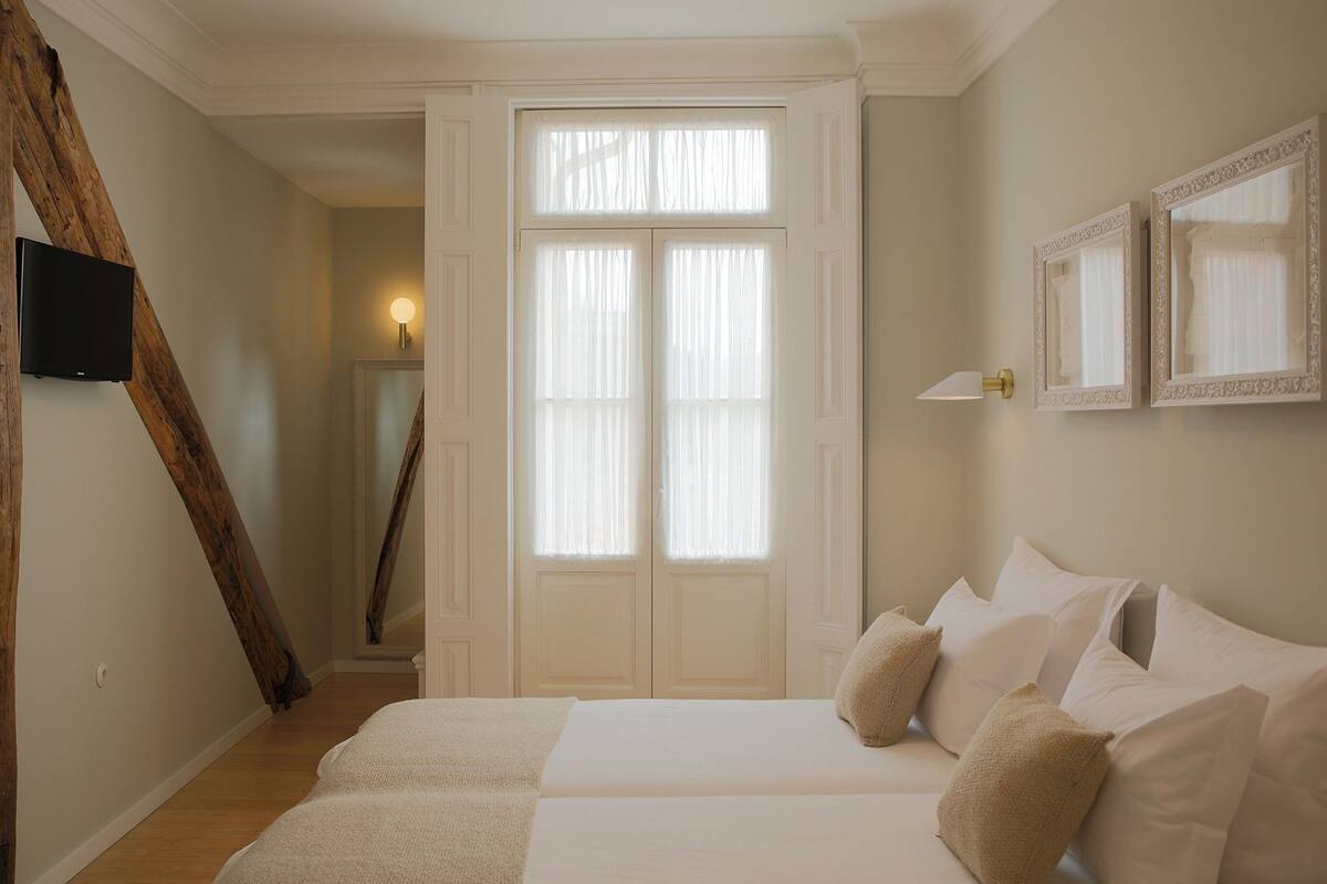 A bedroom with a bed, a television, a door, and a window.