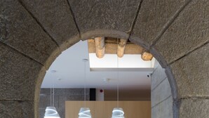 Un interior moderno con suelo de cuadros, paredes de piedra e iluminación colgante.