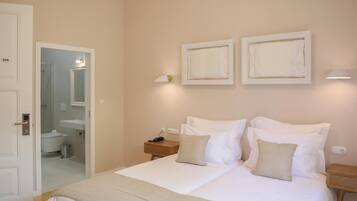 A bedroom with a bed, bedside tables, a nightstand, a mirror, and framed artwork on the wall.