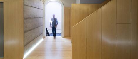A modern interior with a wooden floor, a concrete wall, and a wooden staircase.