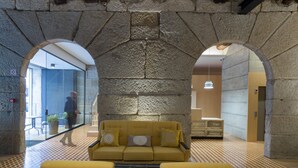 Un vestíbulo con un arco de piedra, un sofá amarillo y un piso a cuadros.