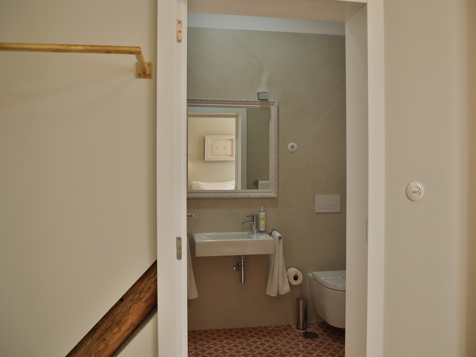 Une salle de bain équipée d’un lavabo, d’un miroir, de toilettes et d’un porte-serviettes.