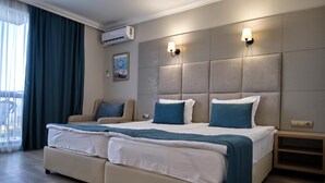 Una cama doble con dos almohadas, un sofá, aire acondicionado instalado en la pared y una mesita de noche.