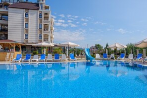 A swimming pool with lounge chairs and umbrellas, surrounded by a multi-story building with balconies. - Veramar Beach (Kranevo)