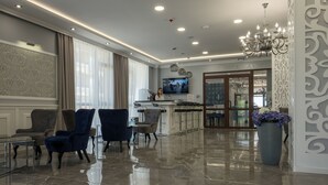 Vestíbulo de hotel con recepción, zona de estar y letrero de restaurante.