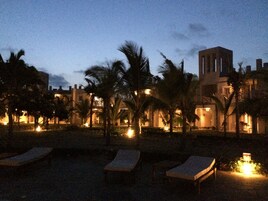 A resort with outdoor seating and palm trees, featuring a building with a tower.