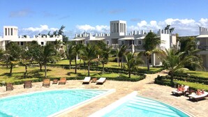 A resort with a pool area, lounge chairs, and a view of the resort's buildings. - Life Resort St.Thomas Royal Palm (Watamu)