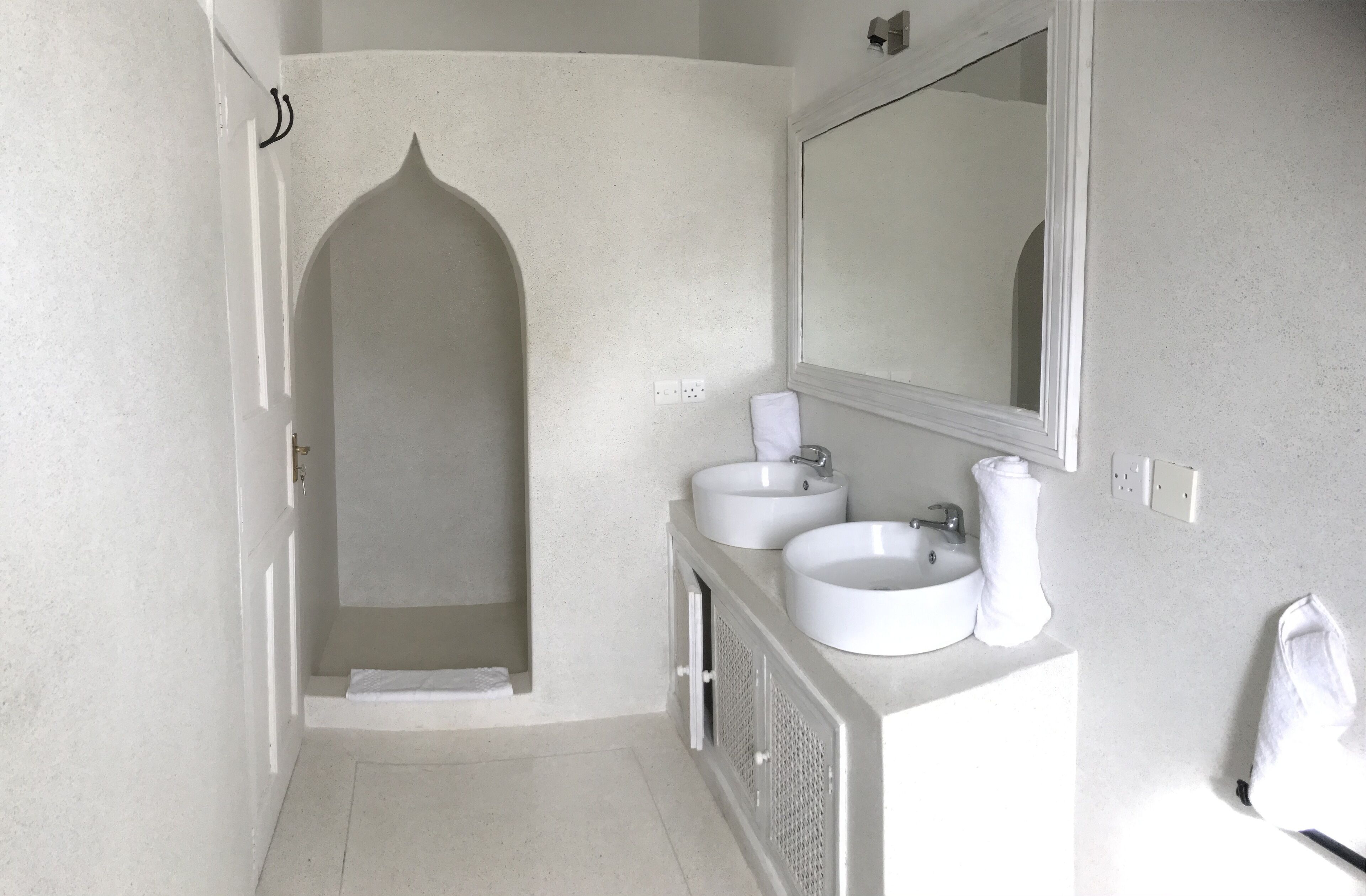 A bathroom with two sinks, a mirror, and a shower area.