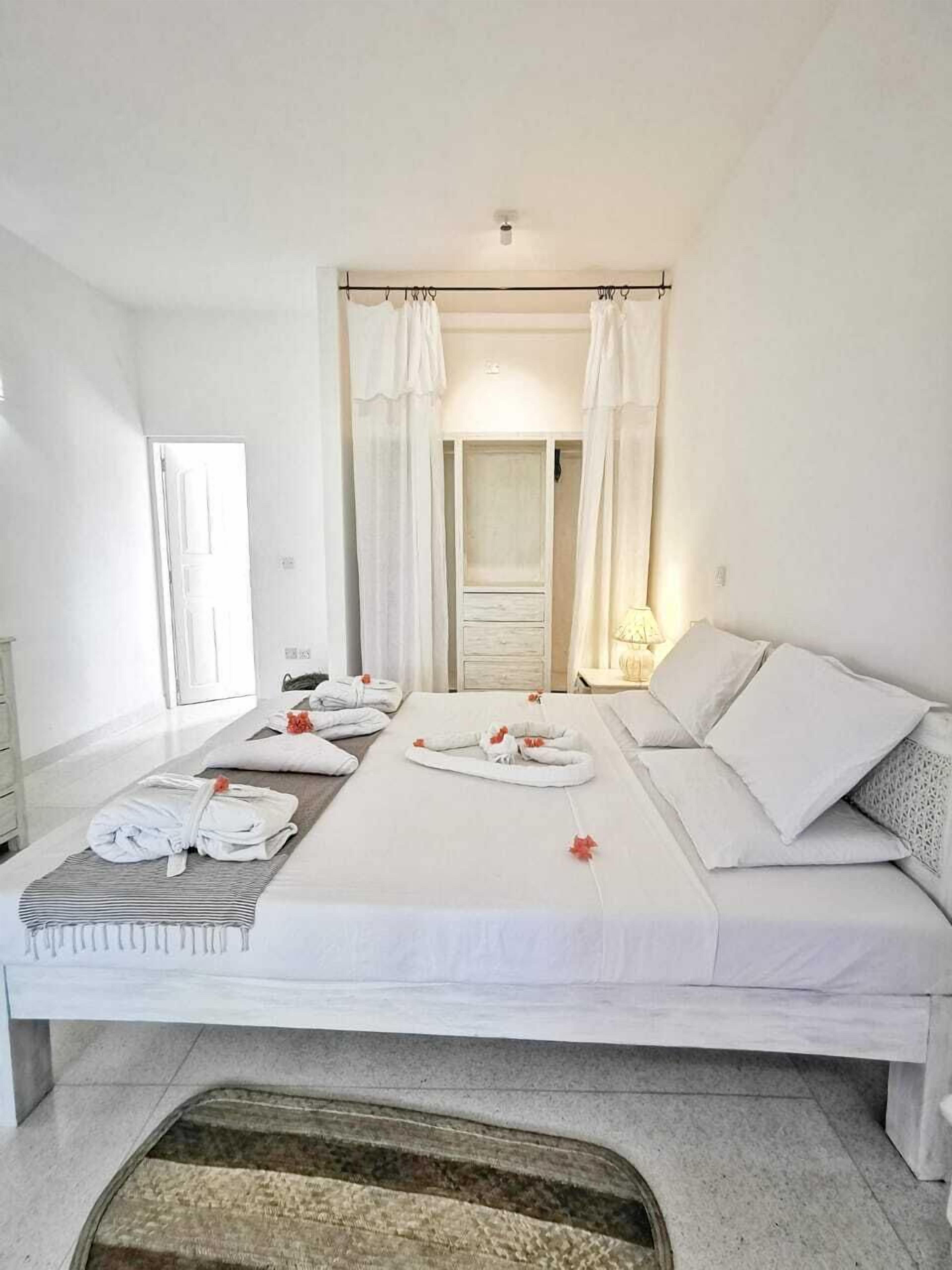 A hotel room with a large bed, a bedside table, a wardrobe, and a window with curtains.
