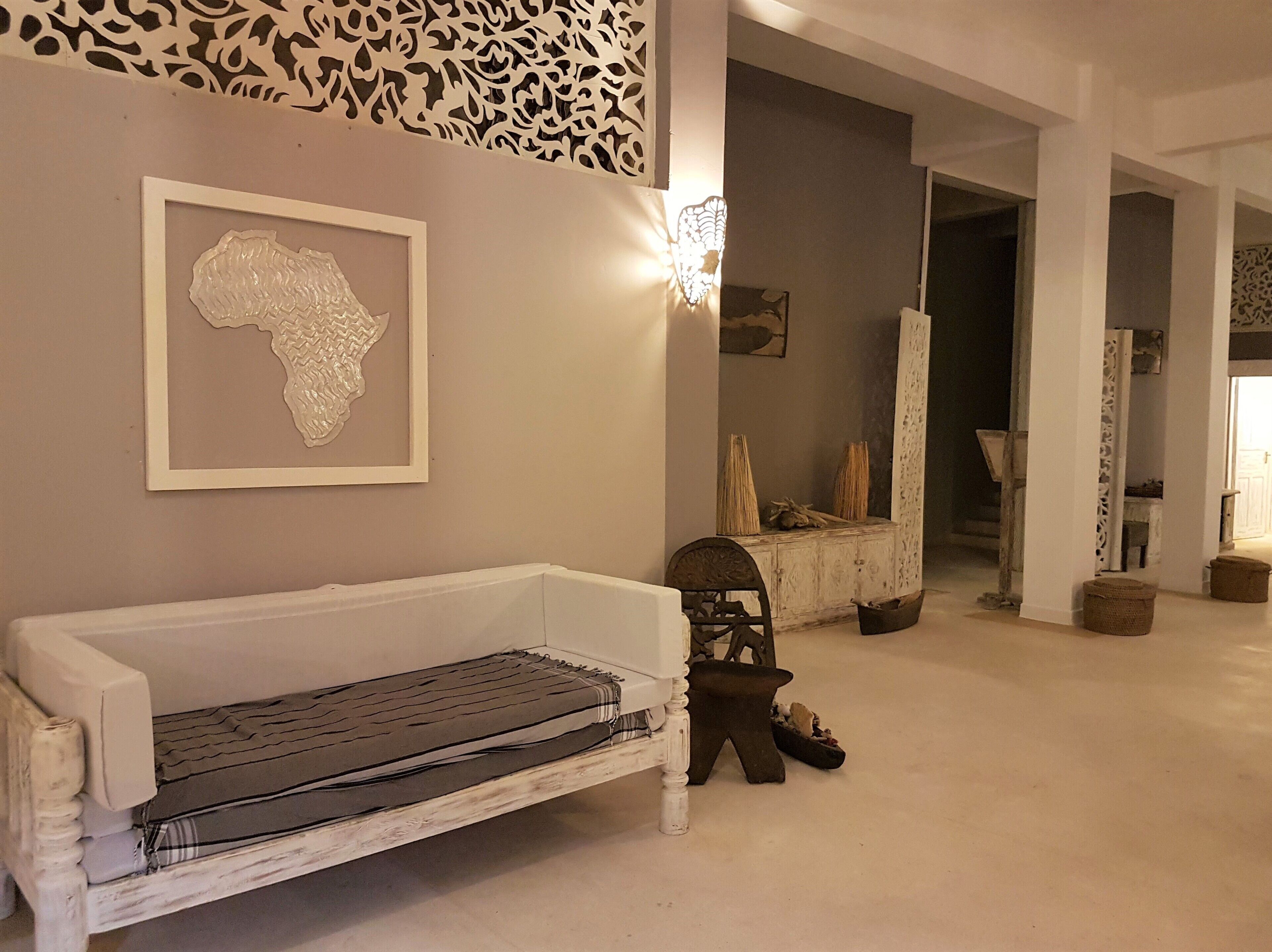 A room with a white bench, a wall-mounted abstract art piece, and a decorative light fixture.