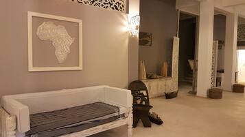 A room with a white bench, a wall-mounted abstract art piece, and a decorative light fixture.