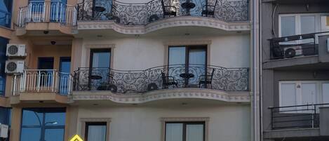 Un hôtel à plusieurs étages, doté de balcons, d’un espace de réception et d’un parking.
