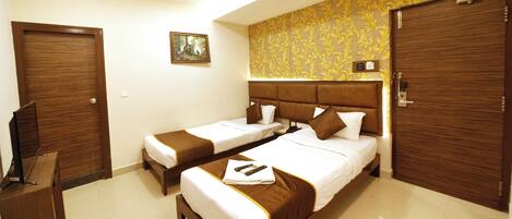 A hotel room with two beds, a ceiling fan, a television, and a painting on the wall.