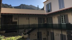 Un edifici amb un balcó, una escala i un paisatge de muntanyes al fons.