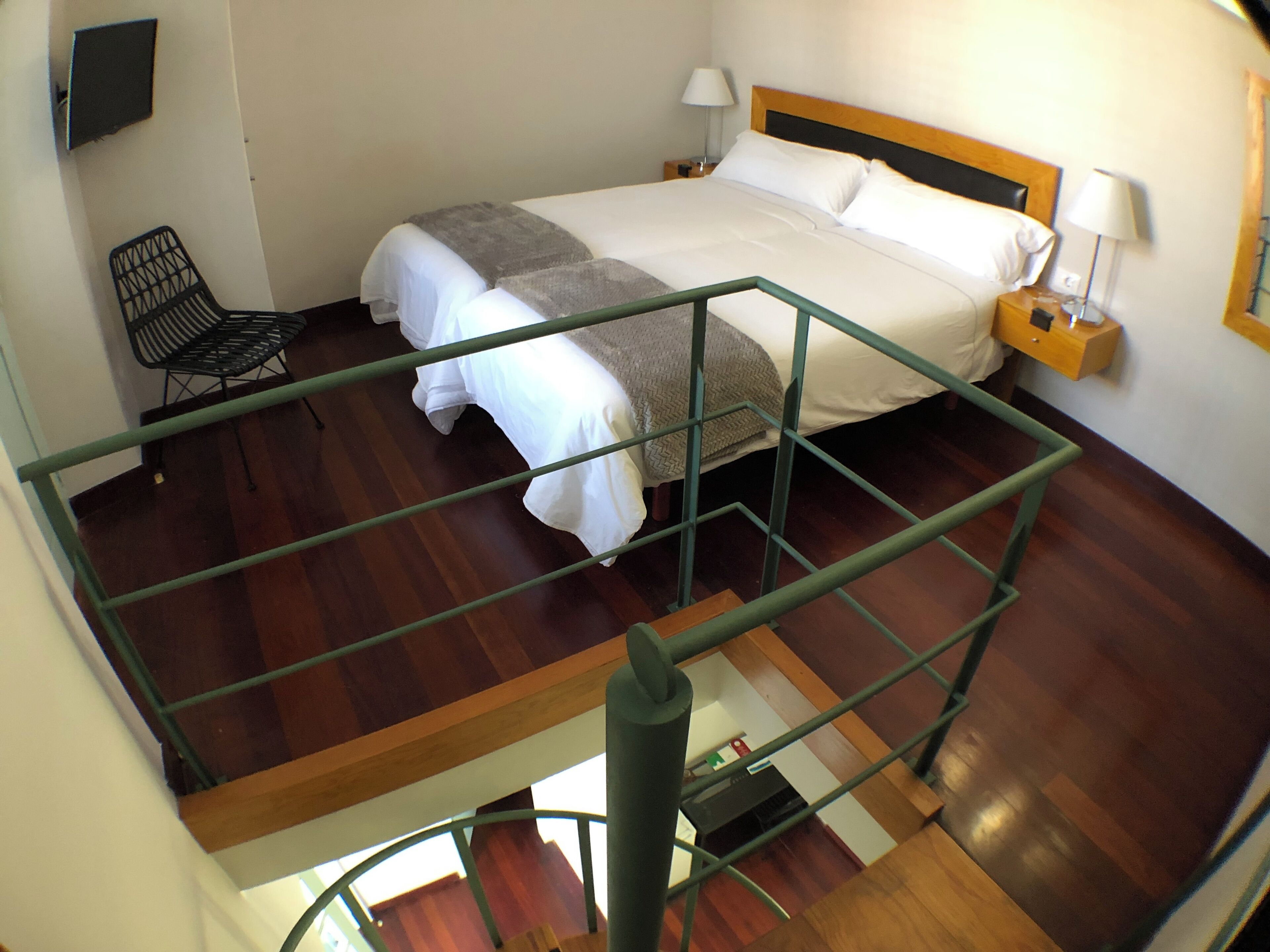 Hotellihuone, jossa on suuri sänky, tuoli, yöpöytä ja lamppu.