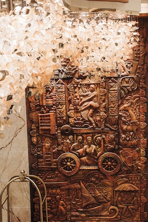 A wall with intricate carvings and a large, ornate mirror. - Park Elanza (Chennai)