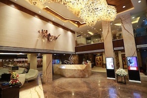 A hotel lobby with a reception desk, seating area, and a decorative ceiling light fixture. - Park Elanza (Chennai)
